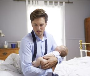 Stressed Father Dressed For Work Holding Baby In Bedroom